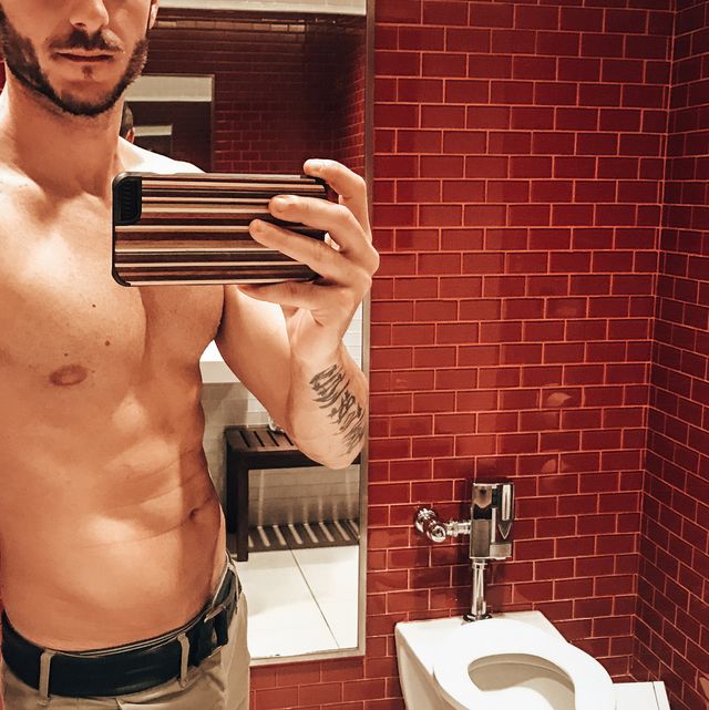 shirtless man take a selfie inside the bathroom