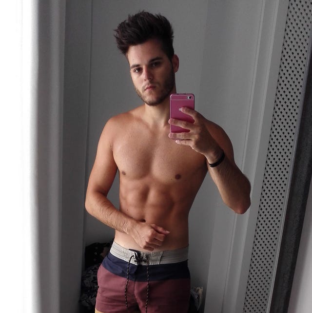 shirtless man taking selfie in mirror reflection at home