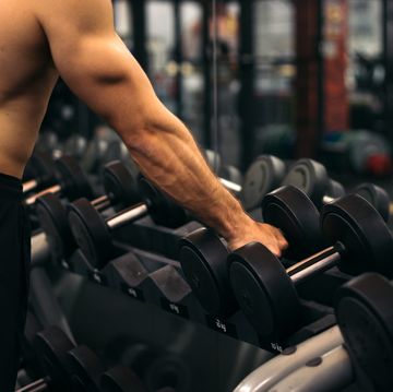 shirtless strong man lifting dumbbell in a gym