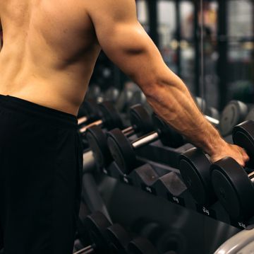 shirtless strong man lifting dumbbell in a gym