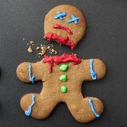 A shocked gingerbread man with broken leg next to a decapitated gingerbread man