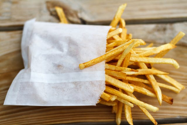 shoestring french fries in white paper bag on picnic table