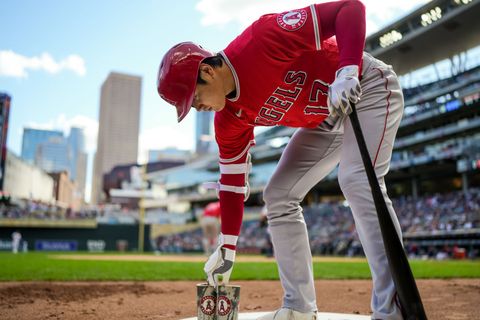 shohei ohtani holding a bat in the on deck circle at a baseball game