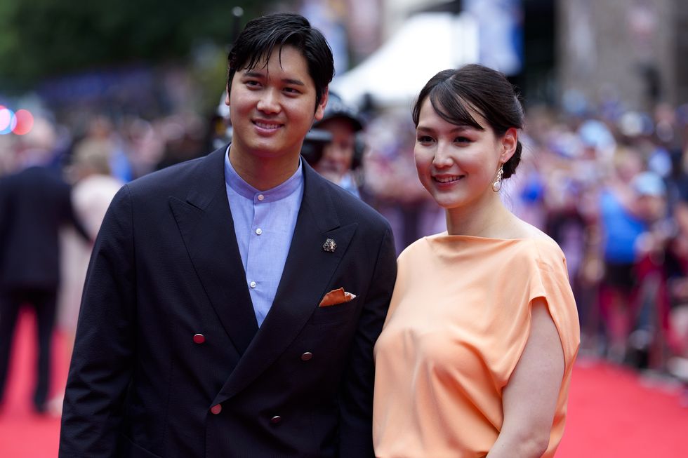 a man and a woman stand close together on a red carpet and smile for photos as they look to the right