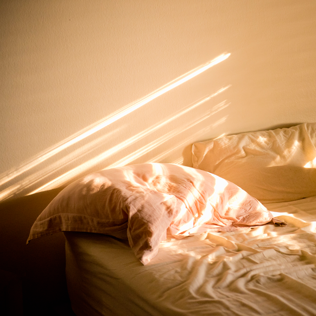 a messy bed with sunlight beams shining in