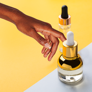 woman's hand touching a bottle of skin serum