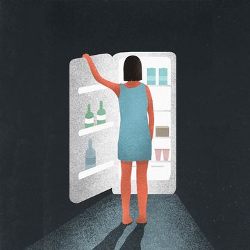 a woman standing in front of refrigerator staring at food at night