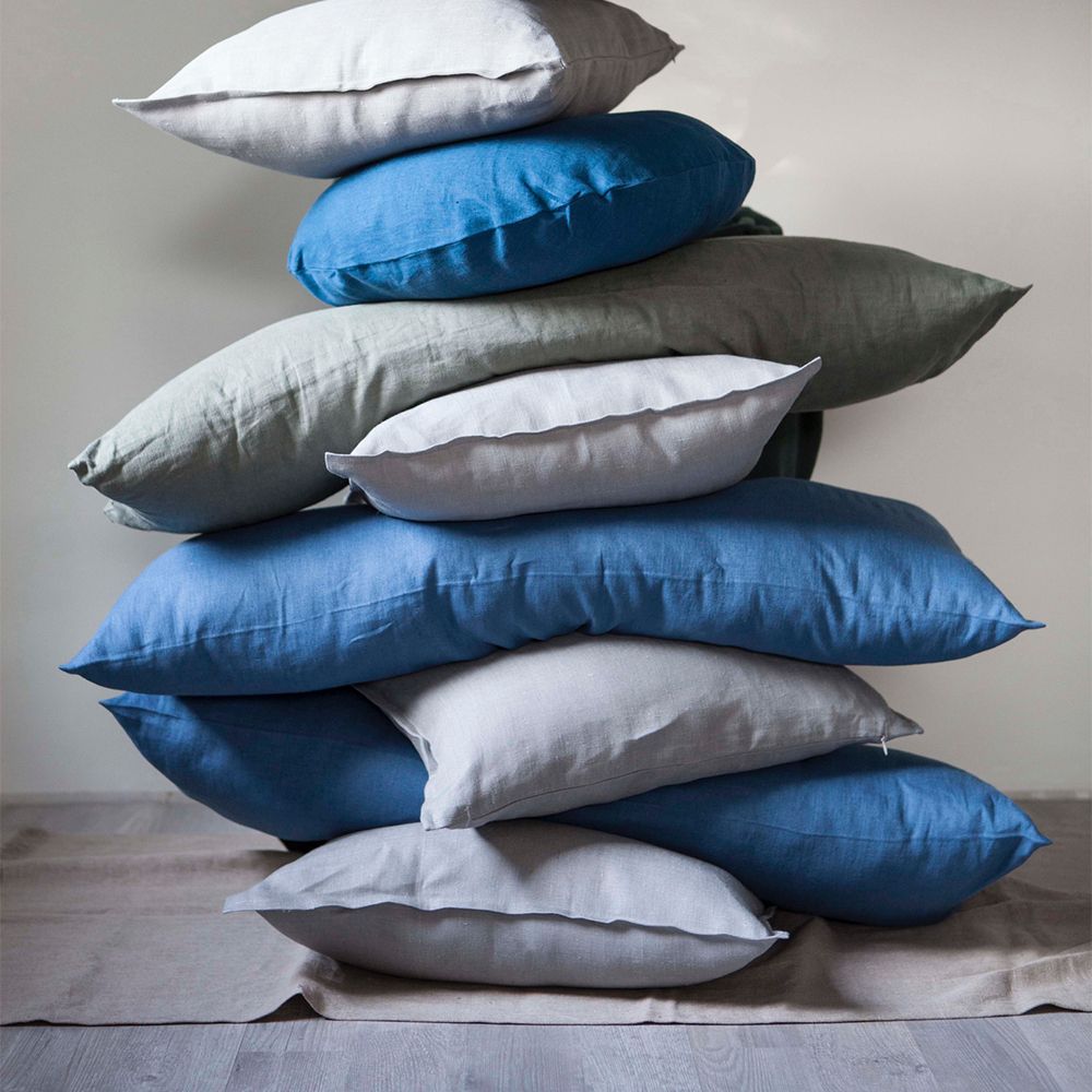 high pile of blue and grey pillows stacked on top of each other