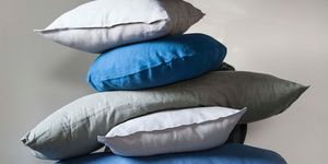 high pile of blue and grey pillows stacked on top of each other