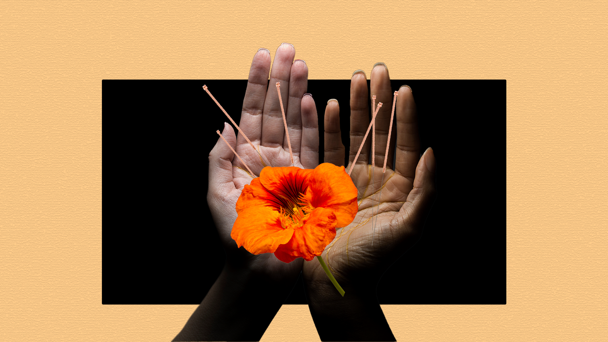 hands holding an orange flower acupuncture needles