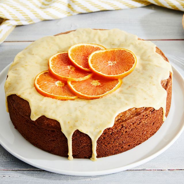 orange cake covered in orange icing with thin slices of oranges