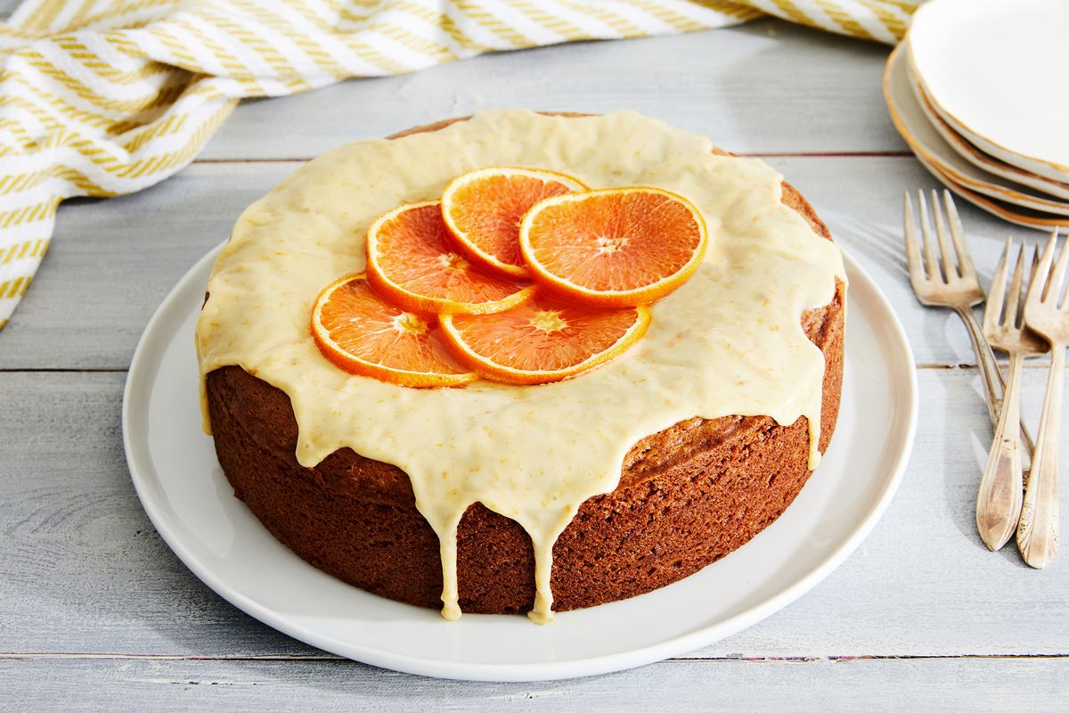 orange cake covered in orange icing with thin slices of oranges