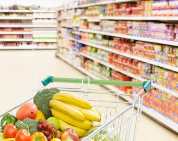 shopping cart in grocery store full of fruits and vegetables