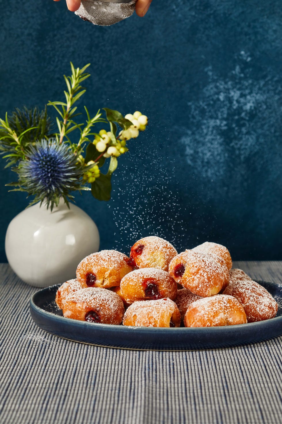 mini sufganiyot on a plate with confectioners' sugar sprinkled on top