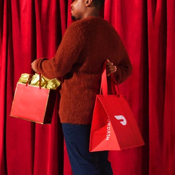 person holding two red bags with a curtain backdrop person holding two red bags with a curtain backdrop