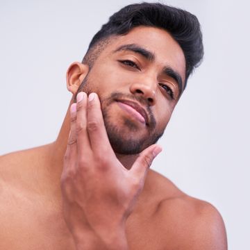 shot of a handsome young man touching his face against a white background