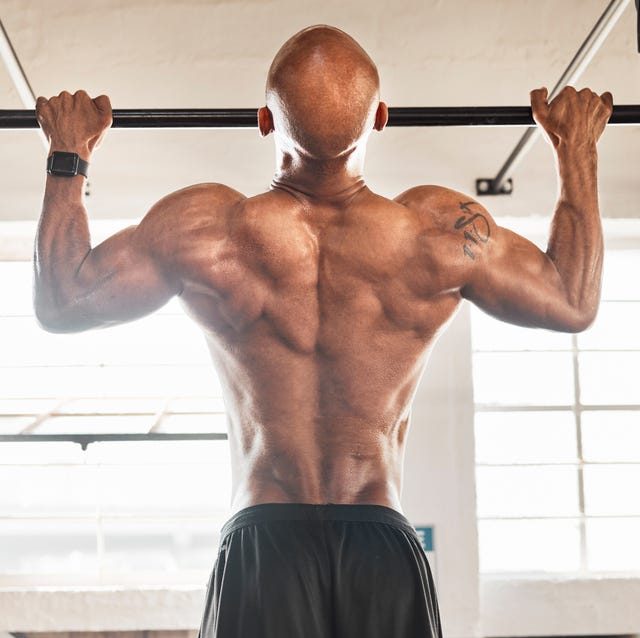 shot of a man completing pull ups in his gym