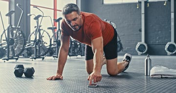 shot of a mature man selecting music from his cellphone before doing mountain climbers during his workout