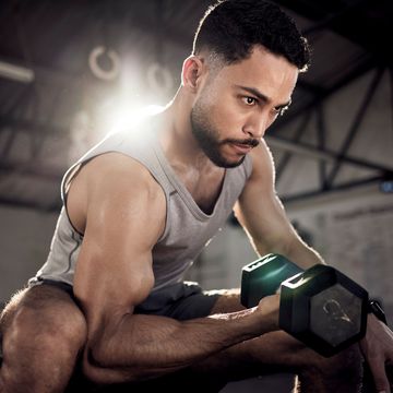 shot of a muscular young man exercising with a dumbbell in a gym
