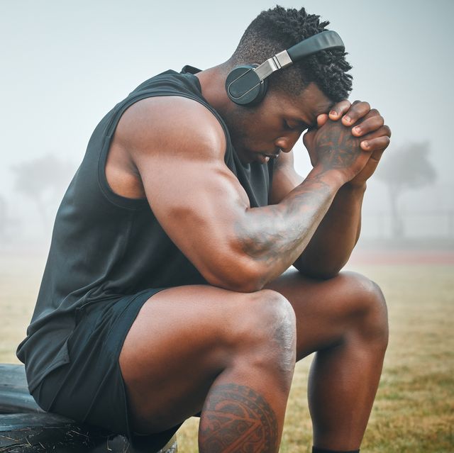 shot of a muscular young man wearing headphones while exercising outdoors