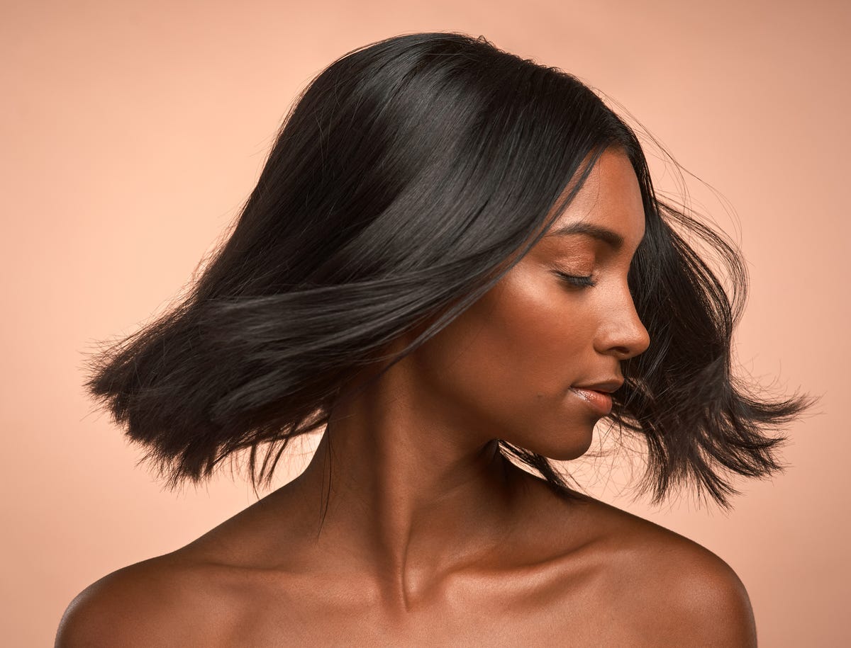 shot of a young attractive woman tossing her hair against a brown background