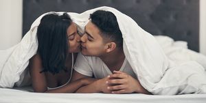 shot of a young couple kissing in bed at home
