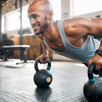 shot of a young man doing weighted push ups using kettlebells