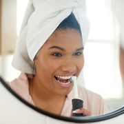 shot of a young woman brushing her teeth with an electric toothbrush at home
