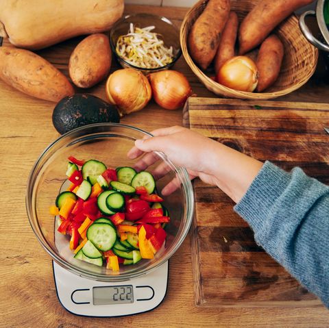 shot of a young woman weighing a bowl vegetables