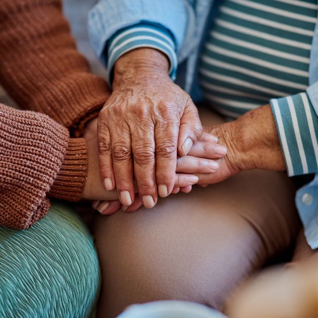 shot of an unrecognisable woman holding hands with her elderly relative on the sofa at home
