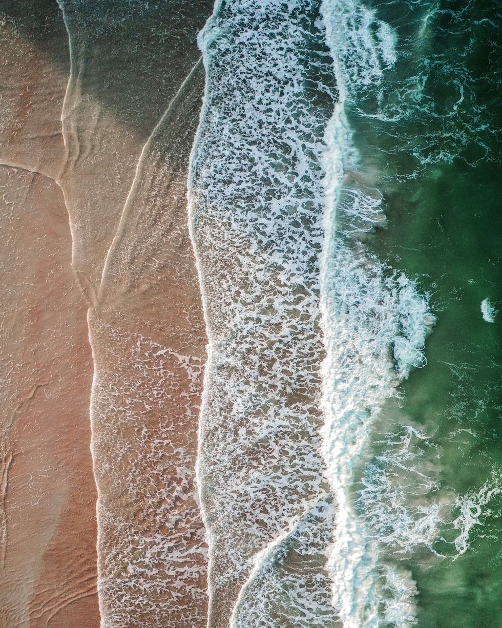 overhead shot of green sea and waves on a beach