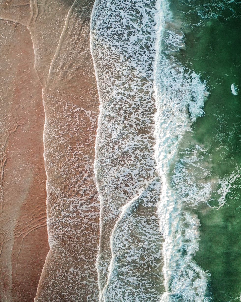 overhead shot of green sea and waves on a beach