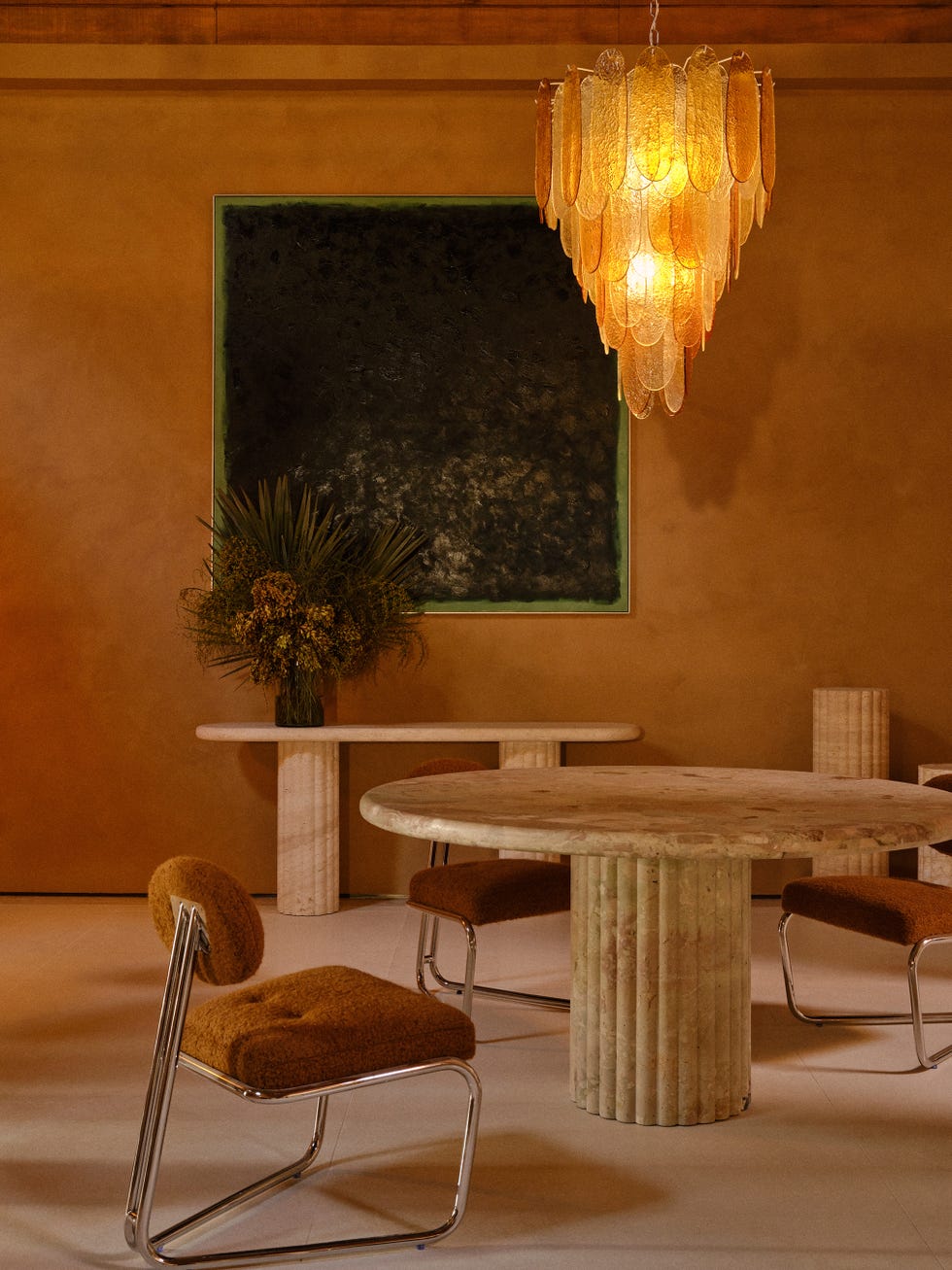 Interior view of the new showroom in Los Angeles with feminine chandelier, stone table, modernist Italian chairs and an abstract green painting