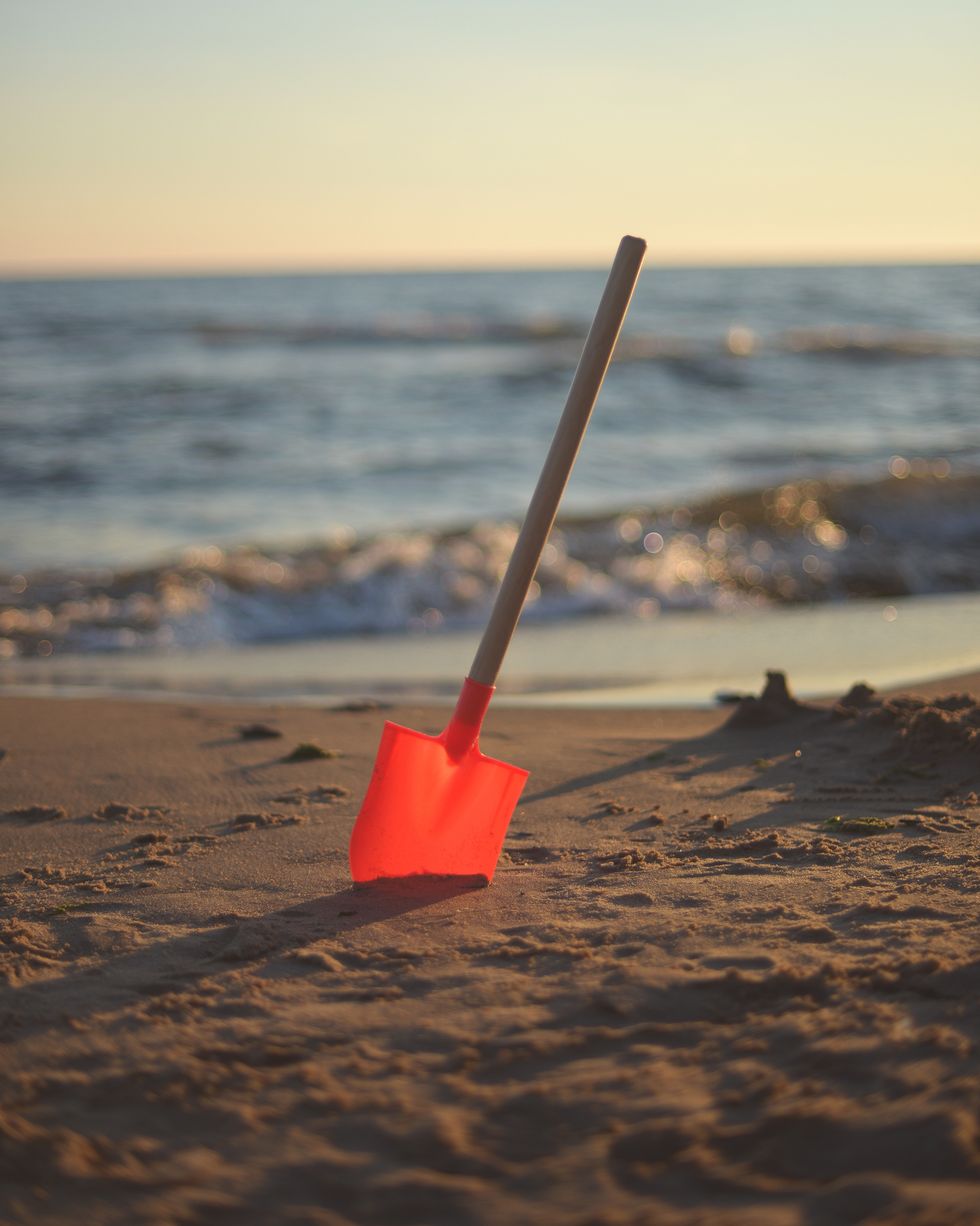shovel in the sand with shoreline in the background