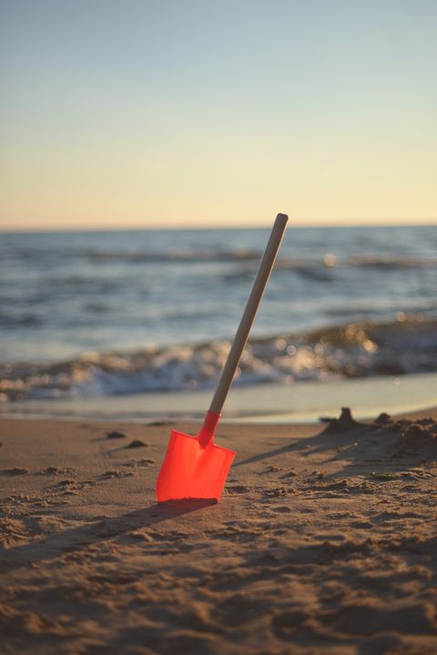 shovel in the sand with shoreline in the background