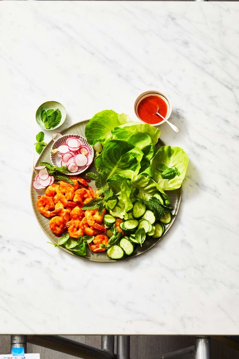 a plate of shrimp, lettuce, cucumbers, and radishes on a plate