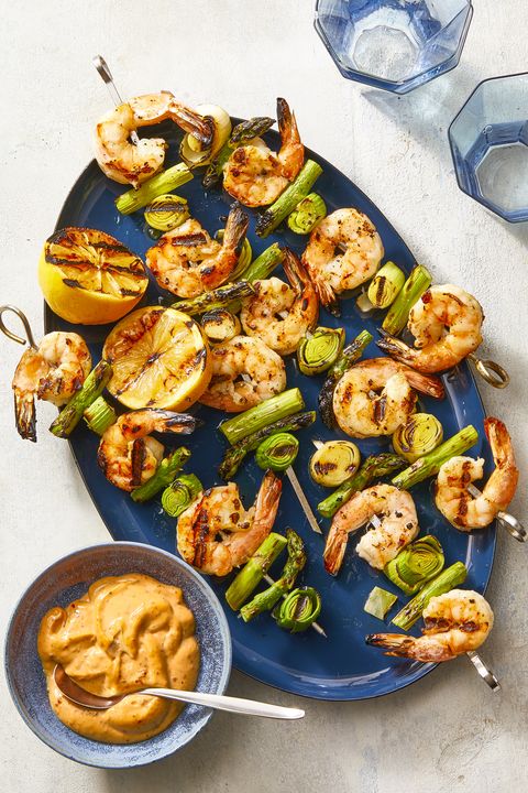 charred shrimp, leek, and asparagus skewers on a blue plate
