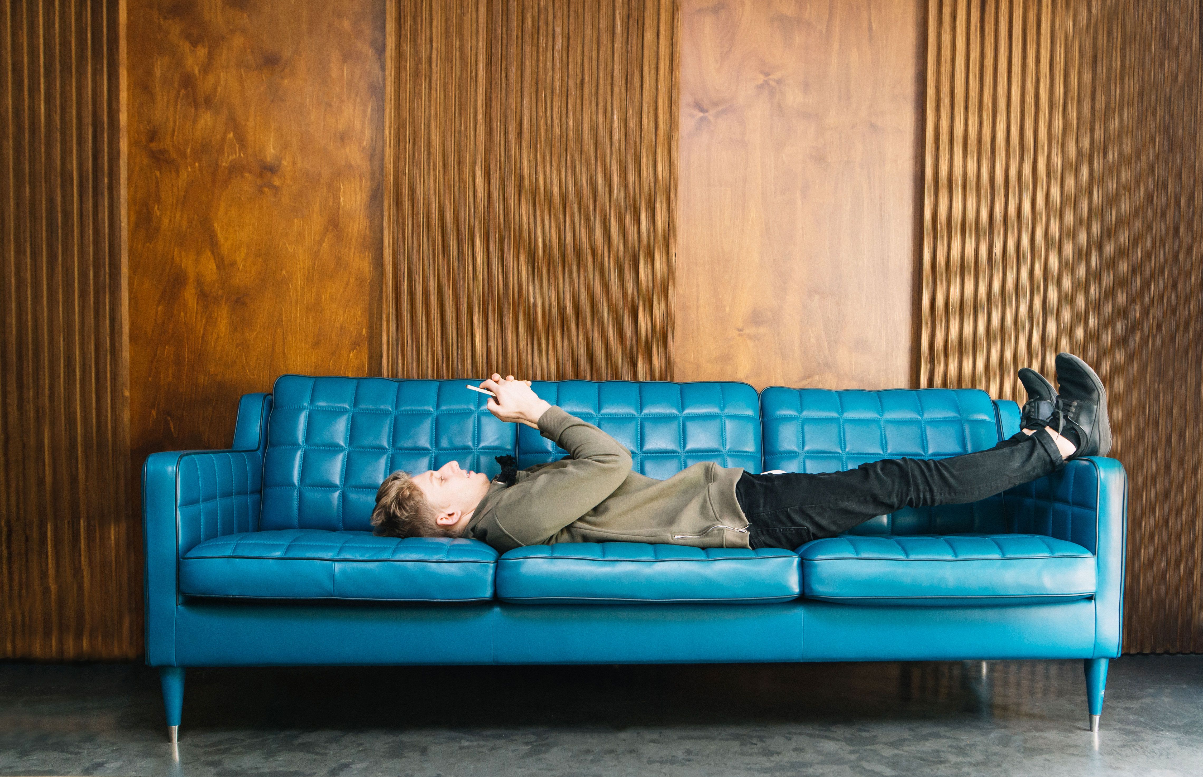 Сколько лет дивану. Человек лежит на диване. Человек отдыхает на диване. Мужчина на диване фотосессия. Человек в интерьере.