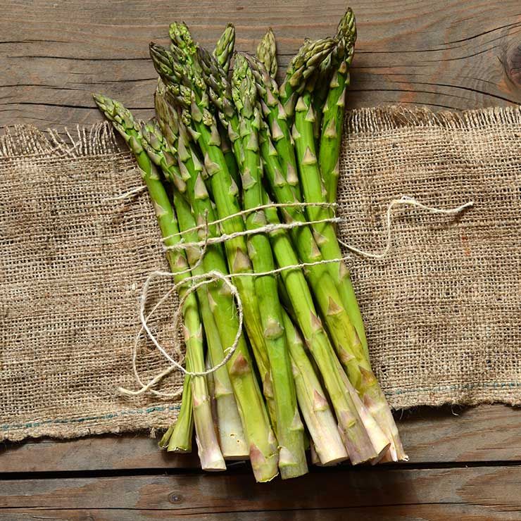 Green asparagus bunch on wicker tray on white table background