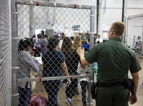 In a photo provided by U.S. Customs and Border Protection, an gent watches as people who've been taken into custody at a facility in McAllen, Texas. 