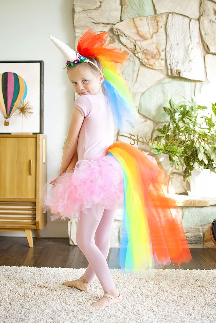little girl dressed in pink tutu and tights, with multicolored tulle for a tail and mane, and a unicorn horn