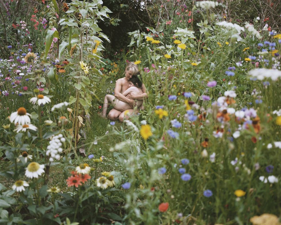 a man and woman sitting in a field of flowers