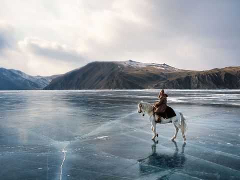 En acteur zit te paard op het Baikalmeer tijdens filmopnamen over de legendarische ruitertocht van een man door Rusland