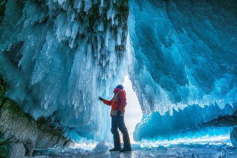 Een man raakt het ijs aan in een grot bij het Baikalmeer