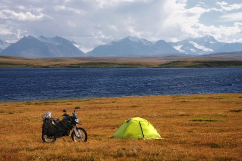 Een motorfiets en tent opgesteld op een hooglandprairie in Siberi