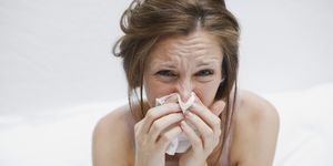 sick woman in bed blowing nose