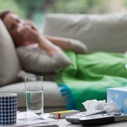 sick woman laying on sofa blowing nose