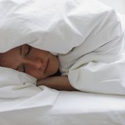 sick woman sleeping in bed under blanket