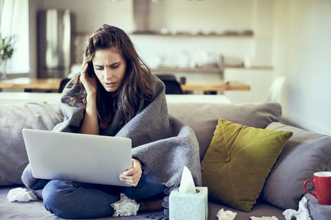 Sick woman trying to work from home on laptop