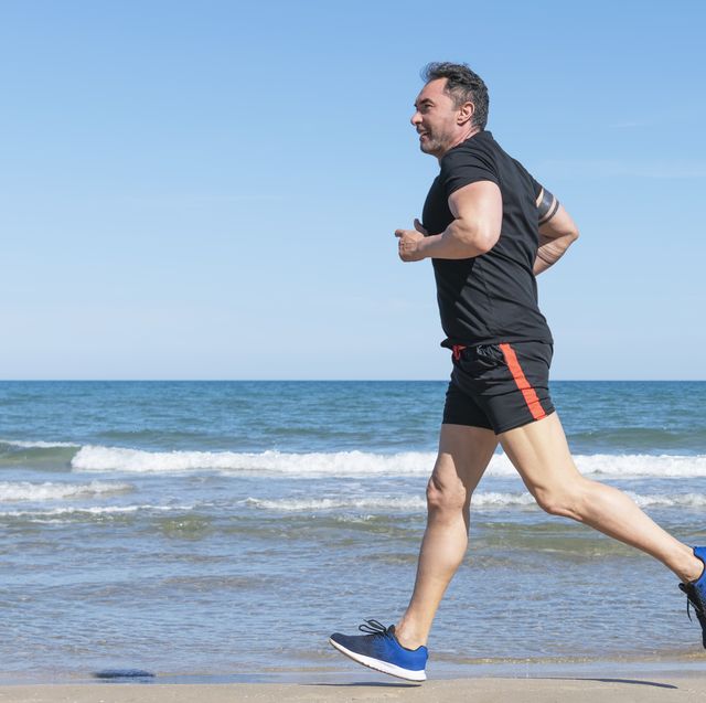 side shot of mature man running along the beach